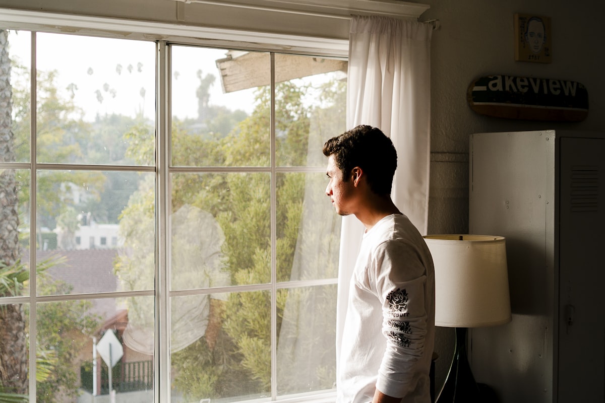 A man alone at a window in morning light